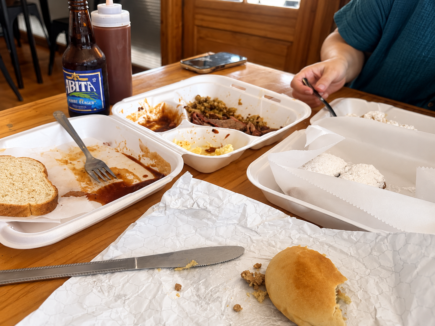 A shared table after a brisket plate lunch with stuffed bread and beignets at Johnson’s Boucanière